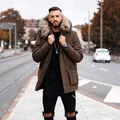 Man wearing a mid-length brown parka with a large fur collar in a city setting - S / Tops / Dark Brown