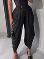 Detalle de elegantes pantalones harem plisados negros con diseño drapeado y un botón dorado. - S / Bottoms / Negro
