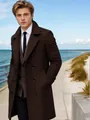 Un bel modello che indossa un elegante trench lungo in lana marrone scuro a doppio petto. - Marrone scuro