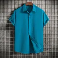 Front view of men's short-sleeved blue button-down shirt on a hanger with grid wall - Teal