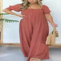 Detail des Jumpsuits mit gesmoktem Oberteil und Puffärmeln in Terrakotta-Farbe. - Orangerot
