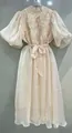 Detalle de un elegante vestido vintage francés con volantes brillantes y mangas abullonadas. - Albaricoque