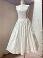 Front detail view of a white halter-neck midi dress with pleated skirt on mannequin - White