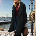 Full view of elegant woman wearing long black teddy coat in a snowy winter scene. - Black