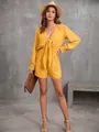 Modella che indossa una tutina gialla a maniche lunghe con fiocco frontale. - Giallo