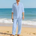 Dettaglio di un uomo che indossa camicia e pantaloni di lino azzurro su una spiaggia sabbiosa - Celeste