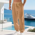 Detailed view of breathable men's linen jogger pants styled in a sunny beach resort setting - Caramel color