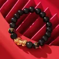 Detailed view of a black Pi Xiu bracelet with golden mantra beads on red background - PiXiu Mantra Bracelet / 10mm