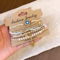 Vintage ethnic beaded bracelet set with Evil Eye and Hamsa charms on kraft card display. - Hamsa Hand / 6-Piece Set / White
