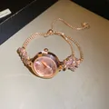 Gros plan d'une montre femme en or rose avec bracelet ajustable orné de fleurs en strass rose - Cadran rond / Or-Rose