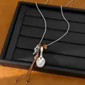 Detail of a silver necklace with spoon pendant and brown leather cord accents. - Spoon Pendant / Silver and Coffee