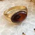 Close-up of gold irregular geometric bangle with a large amber resin oval stone. - Gold-Brown