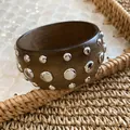 Close-up detail of a dark wood bangle with polished silver metal stud accents - Silver-Coffee