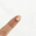 Nahaufnahme eines winzigen goldenen Sternanhängers mit Kristall auf einem Finger - 4# Stern (P6-4) / Minimalist Star