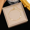 Primer plano detallado de pulsera de acero inoxidable dorado con dijes de flores - Estilo de Trébol de Strass Blanco (E2561) / Dorado