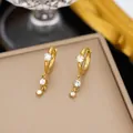 Primer plano de pendientes de acero dorado con circonitas cúbicas colgantes muy brillantes - Estilo Colgante de Strass Triple (G3509) / Dorado