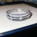 Gros plan d'un élégant bracelet argenté multicouche avec des strass étincelants - Style 63 Jonc (Ouvert à Trois Rangs)