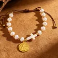 Handcrafted woven rope bracelet featuring baroque pearls, a white cross, and a golden medal. - White (1705)