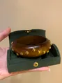 Detailed view of a vintage wooden bangle with gold rivets in a green velvet box - Rivet Wood Style (HB6800-2) / Brown