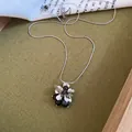 Elegante zilveren bloem hanger ketting met zwarte hars kralen op een getextureerde olijfgroene basis - Bloem Zwarte Kralen-Zilver-Zwart