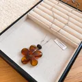 Close-up of a minimalist amber resin flower pendant on a delicate silver chain - Amber Resin Flower Style (73#) / Silver/Coffee