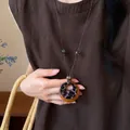 Primo piano di una collana etnica retrò con ciondolo geometrico in legno e resina - Geometrico Leopardato (7#)