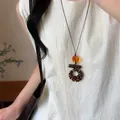 Primo piano di una collana vintage con pendente in legno su un top di lino crema - Colonna Geometrica (8#)