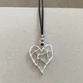 Primo piano di un ciondolo a cuore geometrico traforato in argento con cordino - Cuore Stropicciato (15#)