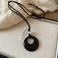Dettaglio di una collana con ciondolo nero circolare in legno e sfera d'argento - Anello Nero Argento (20#)
