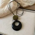 Dettaglio ravvicinato di un ciondolo geometrico in legno su una collana di corda nera - Cordino Tondo Piatto (22#)