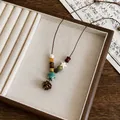 Dettaglio di una collana stile etnico vintage con perle di legno e un ciondolo a stella in ceramica - Ciondolo Pigna (32#)