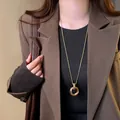 Primo piano di una lunga collana dorata con pendente ad anello geometrico - Geometrico Dorato (34#)