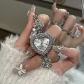 Macro view of a heart-shaped rhinestone watch with flower charms on a silver bracelet. - Bracelet Watch - Silver