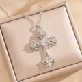 Primer plano detallado de un colgante de cruz floral calada en plata con circonitas. - Estilo de Cruz de Plata