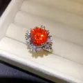 Nahaufnahme eines funkelnden orangefarbenen Zirkonia-Blumenrings in einer Schmuckschatulle - Blumenstil / Silber-Orangerot