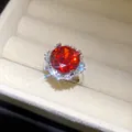 Nahaufnahme eines luxuriösen Rings mit rotem Zirkon in einer cremefarbenen Schmuckschatulle - Blumenstil / Silber-Rot