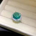 Nahaufnahme eines runden smaragdgrünen Zirkonrings mit funkelnder Blütenfassung - Runder Stil / Silber-Grün