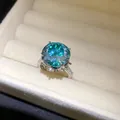 Primer plano de un anillo de plata con un gran circón turquesa y piedras pavé. - Estilo de Flor / Plata-Azul