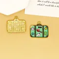 Macro view of mint green enamel suitcase pendant with 'TRAVEL' text and golden textured charm - Green