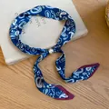 Blaue Paisley-Seidenschal-Halskette mit Perle auf vintage Buchhintergrund - Halskette-Blau-Paisley