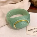 Detailansicht eines grünen Acryl-Armreifs mit Marmoreffekt und einer goldfarbenen Metalleinfassung. - Armreif / Grün