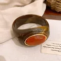 Nahaufnahme eines Vintage-Acryl-Armreifs mit marmoriertem Design und orangefarbenem Stein - Armreif / Dunkler Kaffee und Orange