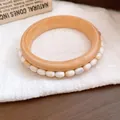 Detailansicht eines Vintage-Armreifs im Holzstil mit weißen Steinen auf weißem Leinen. - Natürliche Retro Muscheldekoration / Khaki-Weiße Perlen