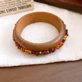 Makroansicht eines Retro-Holzarmreifens mit eingebetteten Bernsteinsteinen - Walnuss Bernstein Perlenarmband / Walnuss-Bernstein