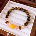 Close-up detail of tiger eye stone beaded bracelet with yellow accent bead in a jewelry box. - 10mm