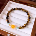 Close-up of high-quality tiger's eye beaded bracelet with yellow accent bead in wooden box - 8mm