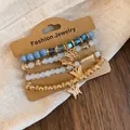 Détail d'un ensemble de quatre bracelets bohèmes avec pendentifs papillons dorés et perles - Or, Bleu Et Café