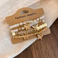 Gros plan d'un ensemble de bracelets bohèmes avec des breloques papillons dorés - Ensemble de 4 Bracelets Bohémiens / Or, Blanc Et Café