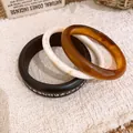 Detailansicht eines dreiteiligen Armreifsets aus Harz und Holz mit feinen Strukturen. - Dreiteiliges Set / Braun-Kaffee-Off-White