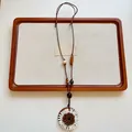 Vista dettagliata di una collana lunga con ciondolo a forma di girasole in tessuto bianco. - Ciondolo Girasole (XL4662)